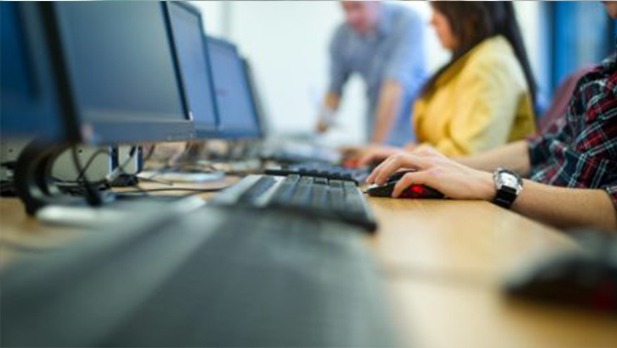 students typing on a row of desktop computers