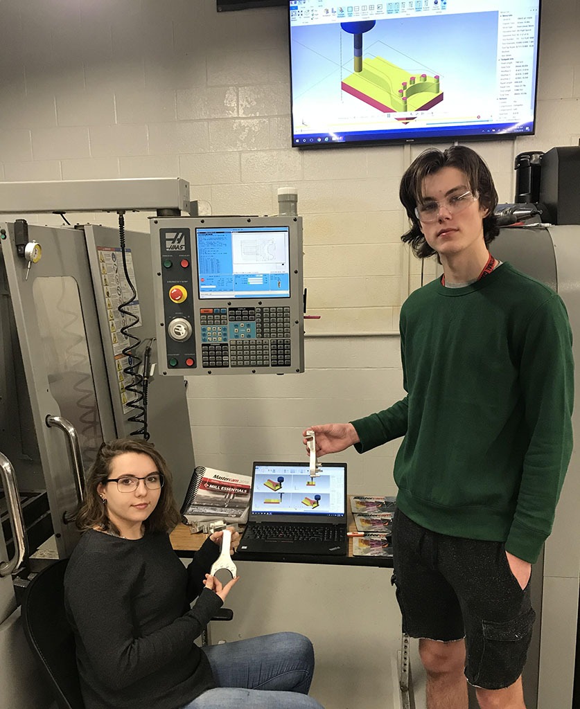 One male and one female glove aid students using mastercam software on a laptop