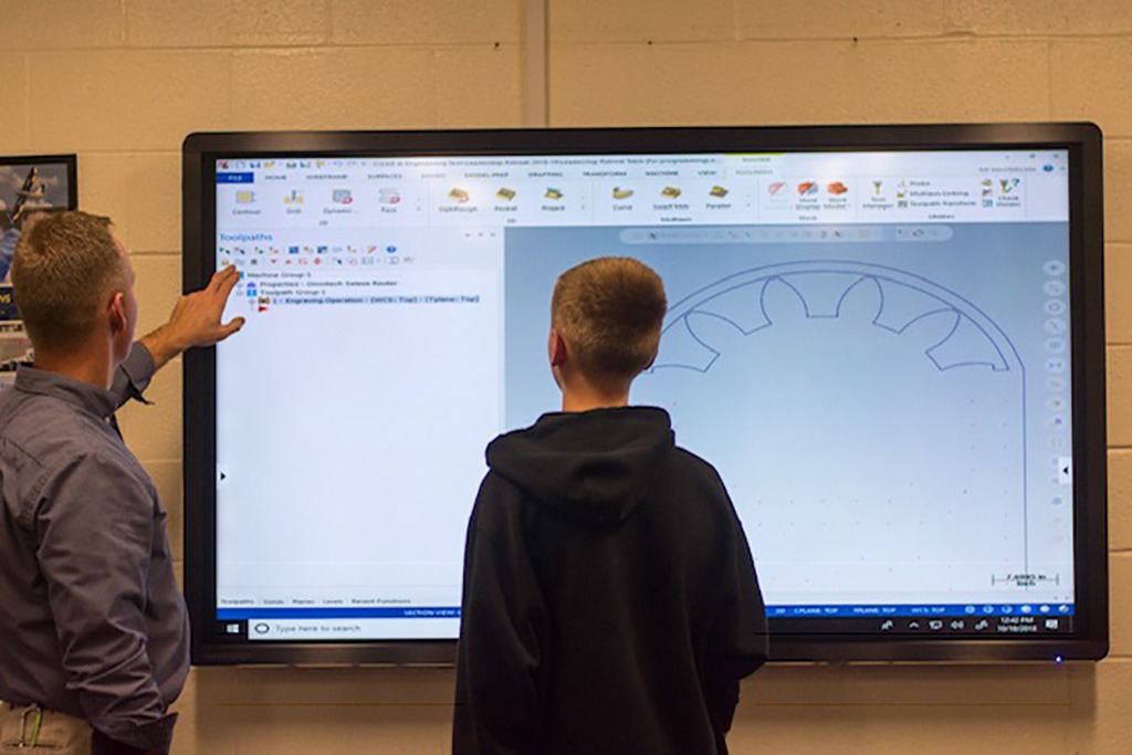 A male teacher instructing a male student at a the board