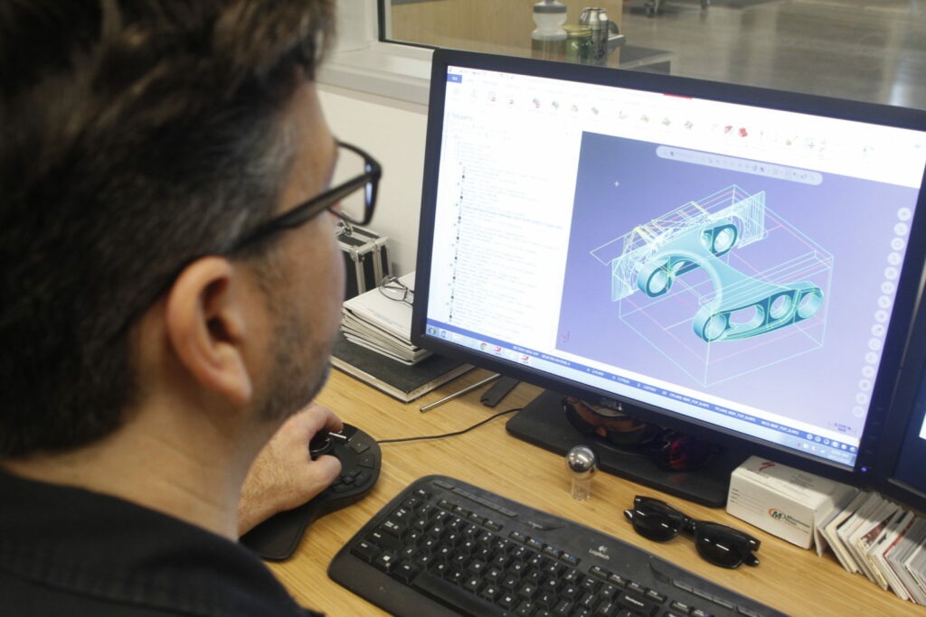 Male sitting at a desk using a 3D model software for mechanical parts