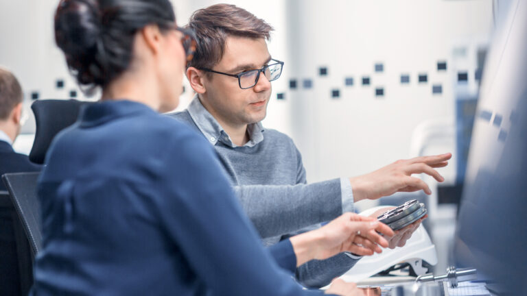 Photo of a man and a woman pointing to a computer screen