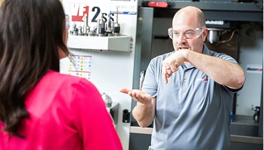 Man in safety glasses talking to a woman