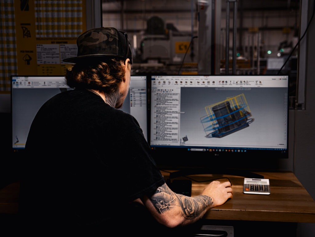 homme dans un atelier d'usinage regardant deux écrans utilisant le logiciel mastercam