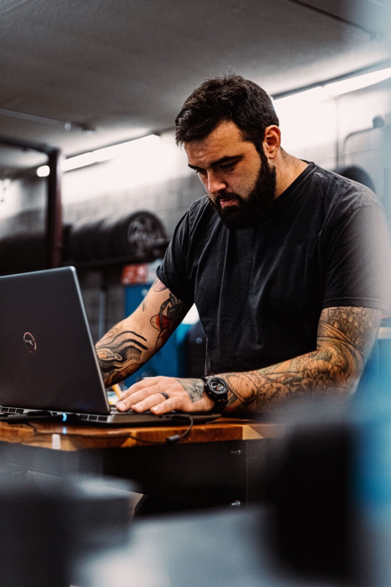 Man standing in a workshop, working on a laptop computer